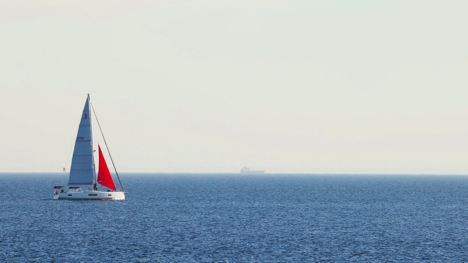 sailboat-with-red-white-sails-calm-blue-ocean